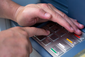 Ladies hand dials the PIN code at an ATM